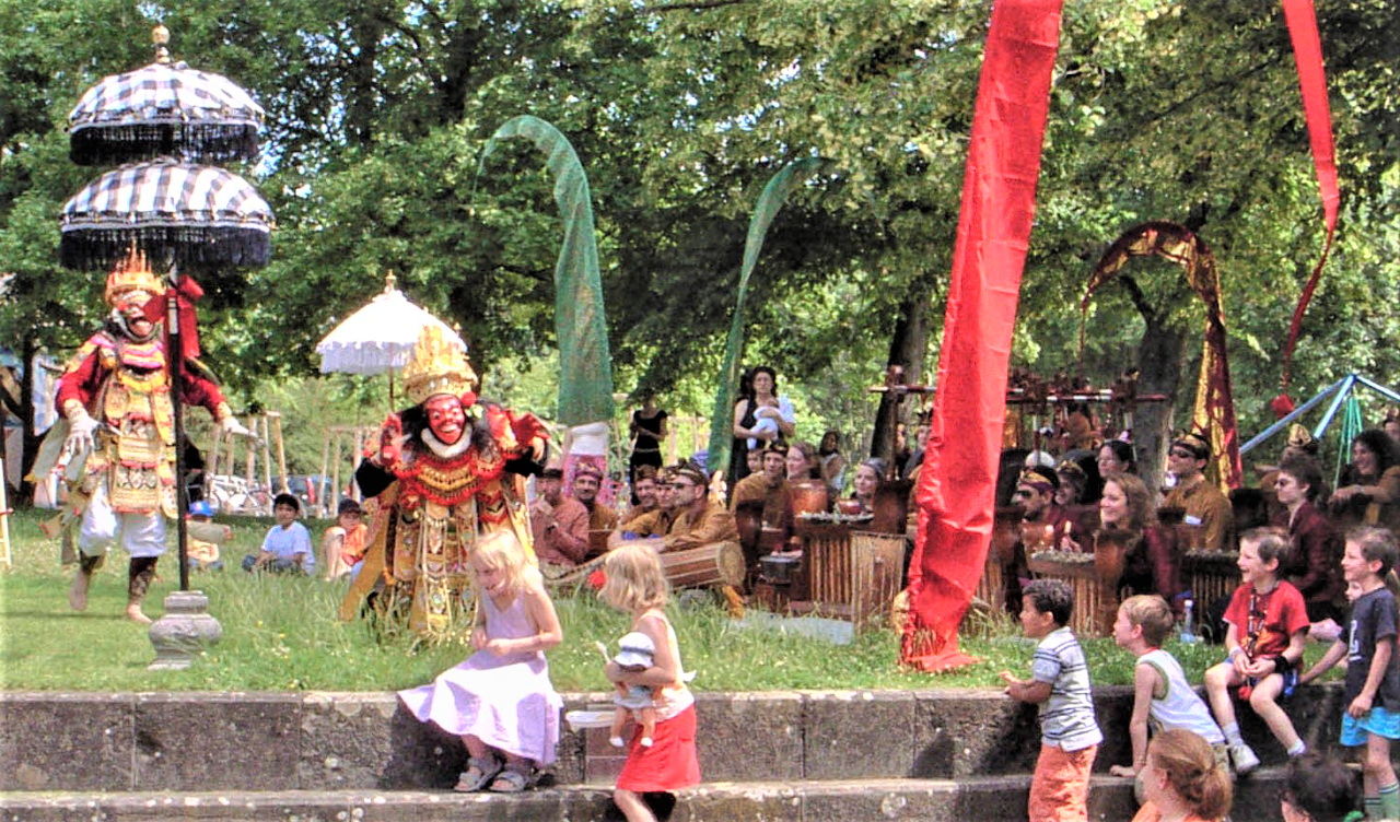 Verkleidete balinesische Figuren gehen auf Kinder zu